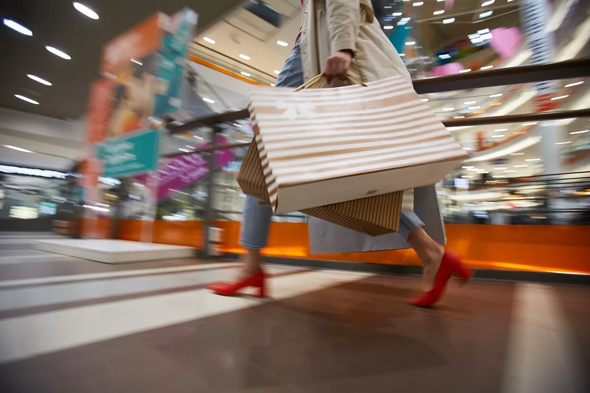 mujer con efecto movimiento en centro comercial con bolsas en mano